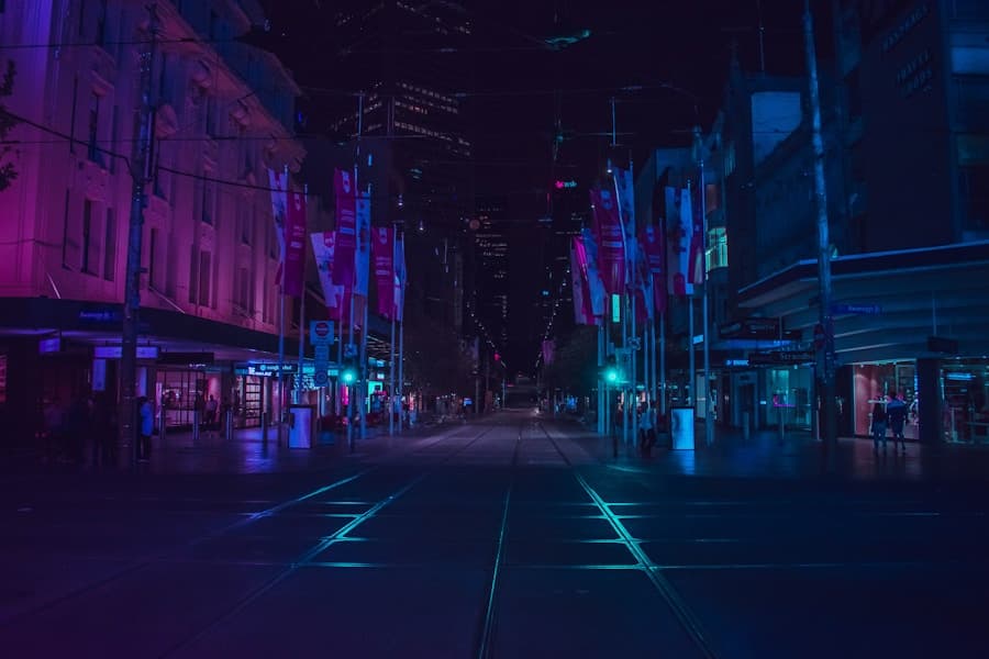 A city street at night lit by violet and blue neon